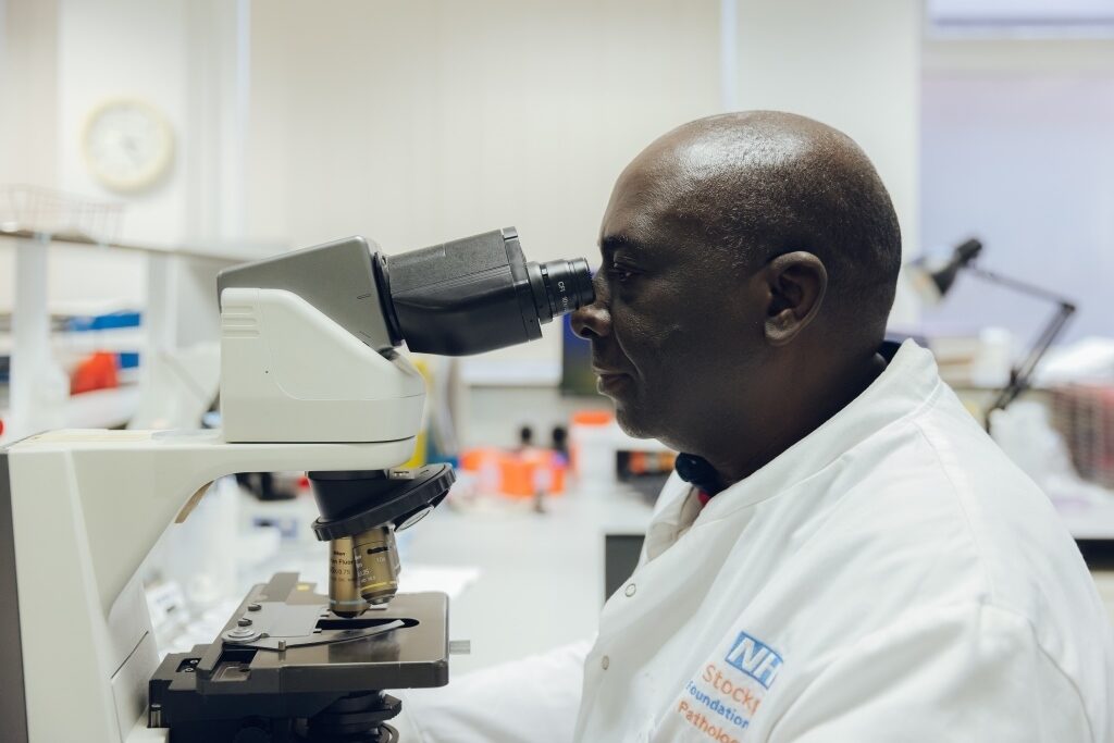 Man in lab coat looking through microscope