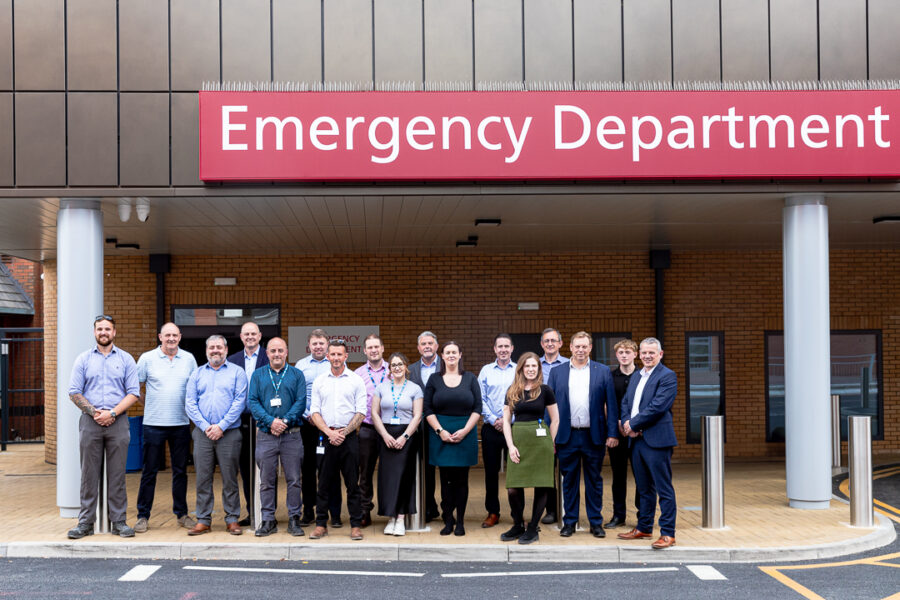 A group of men and women outside underneath a sign saying 'Emergency Department'